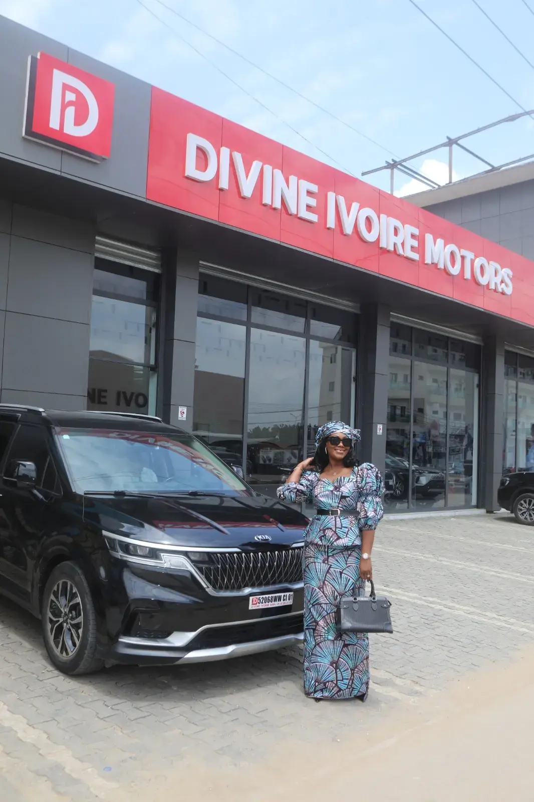 Grace Divine TEKY devant l'enseigne du showroom Divine Ivoire Motors à Abidjan