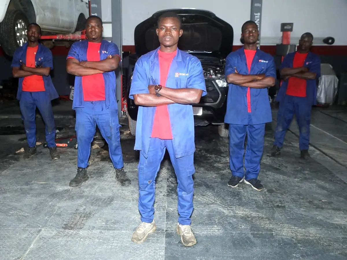 L'équipe de mécaniciens de Divine Ivoire Motors dans l'atelier, devant un véhicule au pont élévateur